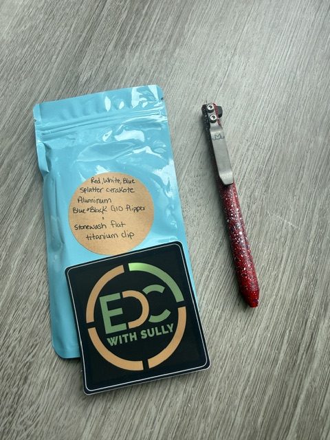 Blue resealable pouch with an orange list of materials, next to a square EDC with Sully logo and a pink glittery pen-like tool on a wooden surface.