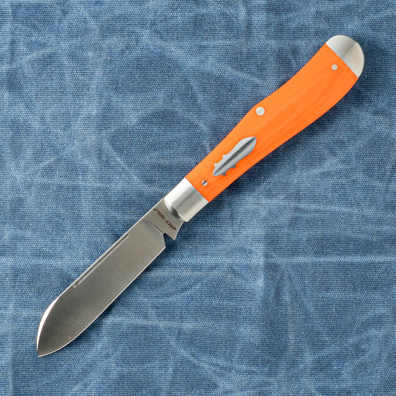 Orange-handled folding knife with a silver blade opened, resting on blue fabric.