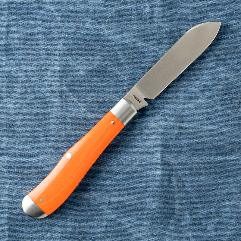 Chef knife with an orange wooden handle on a blue fabric background.
